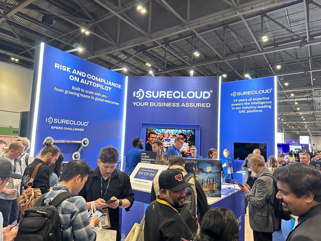 Crowd gathered at the SureCloud booth at Infosecurity Europe 2025, featuring product demos and GRC platform messaging. 