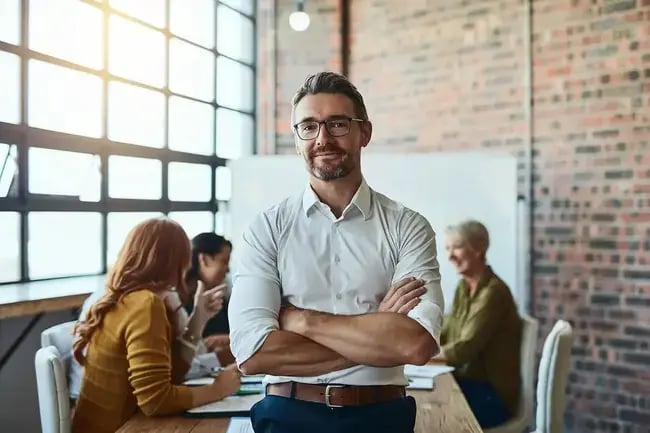 Stock - man in modern office space with colleagues behind